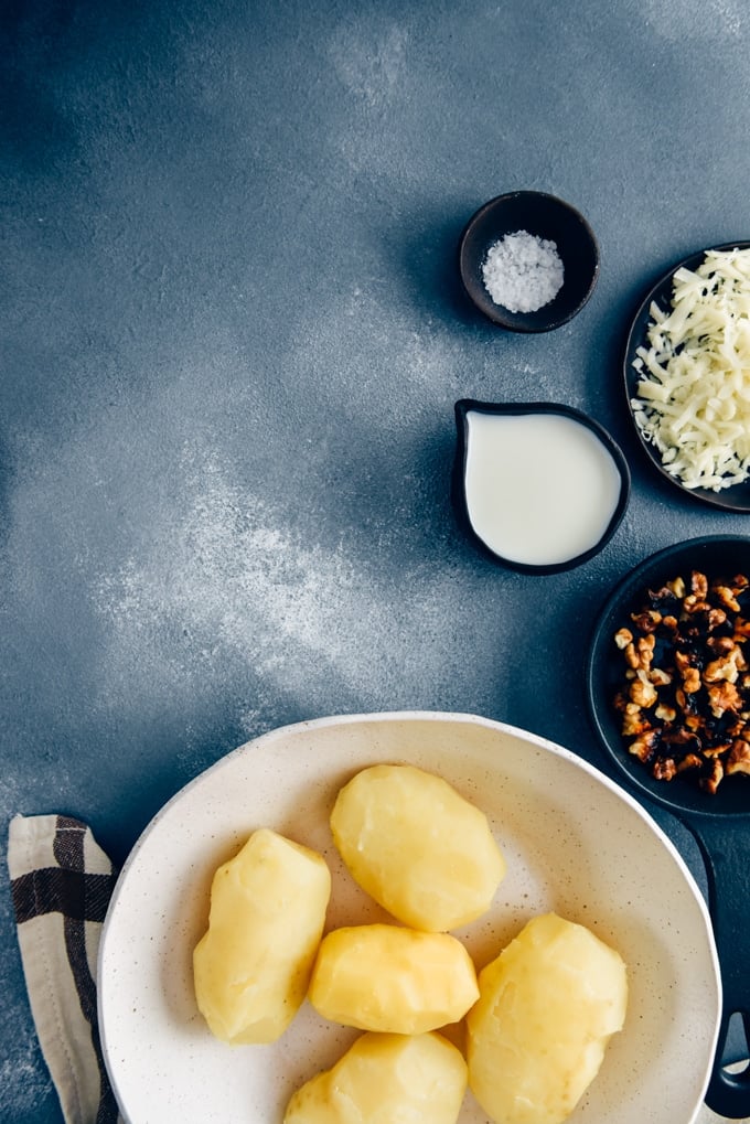在一个白色的陶瓷碗里煮熟并削了皮的土豆，在黑色的背景上做奶酪土豆泥。