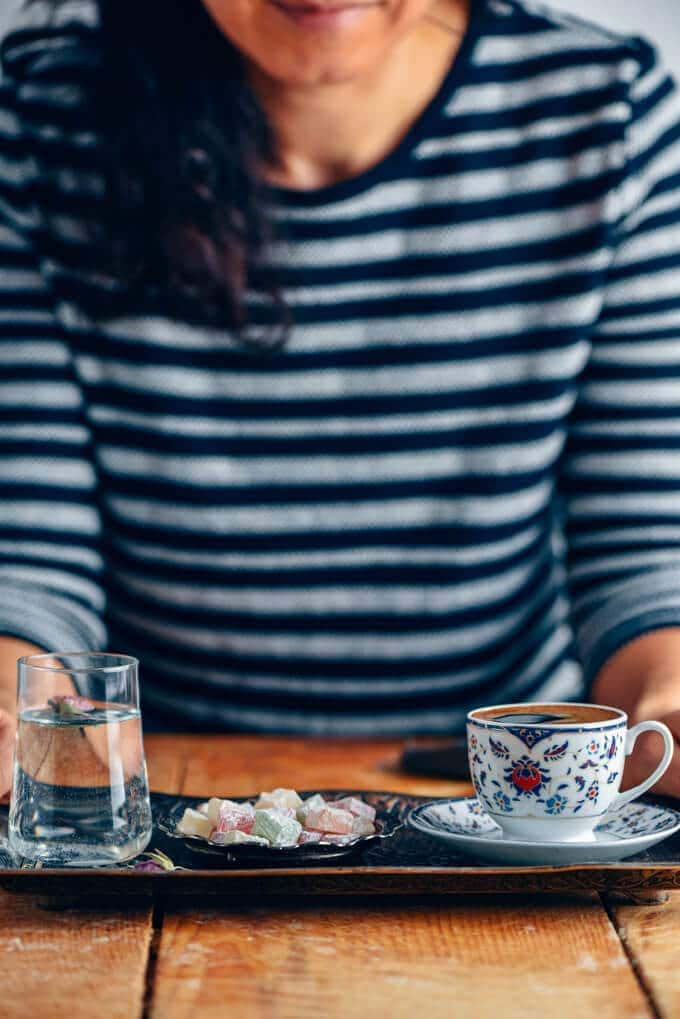 女子服务土耳其咖啡与土耳其的喜悦和一小杯水在旁边的铜托盘。