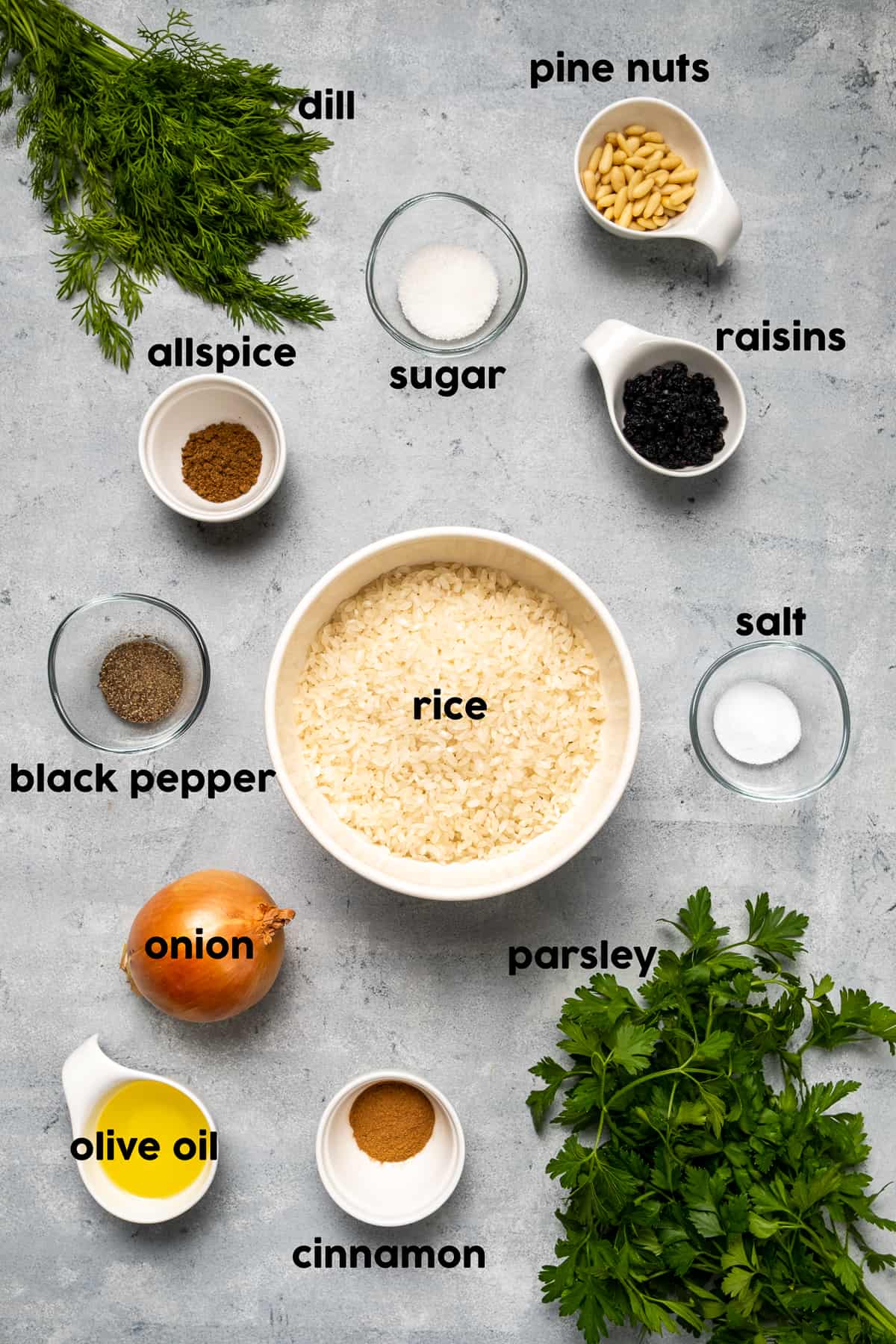 把米饭放在一个大碗里，松子、葡萄干、莳萝和欧芹、香料、洋葱和橄榄油放在灰色的背景上。