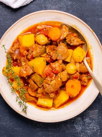 羊肉炖土豆和胡萝卜在一个大碗和勺子在它。