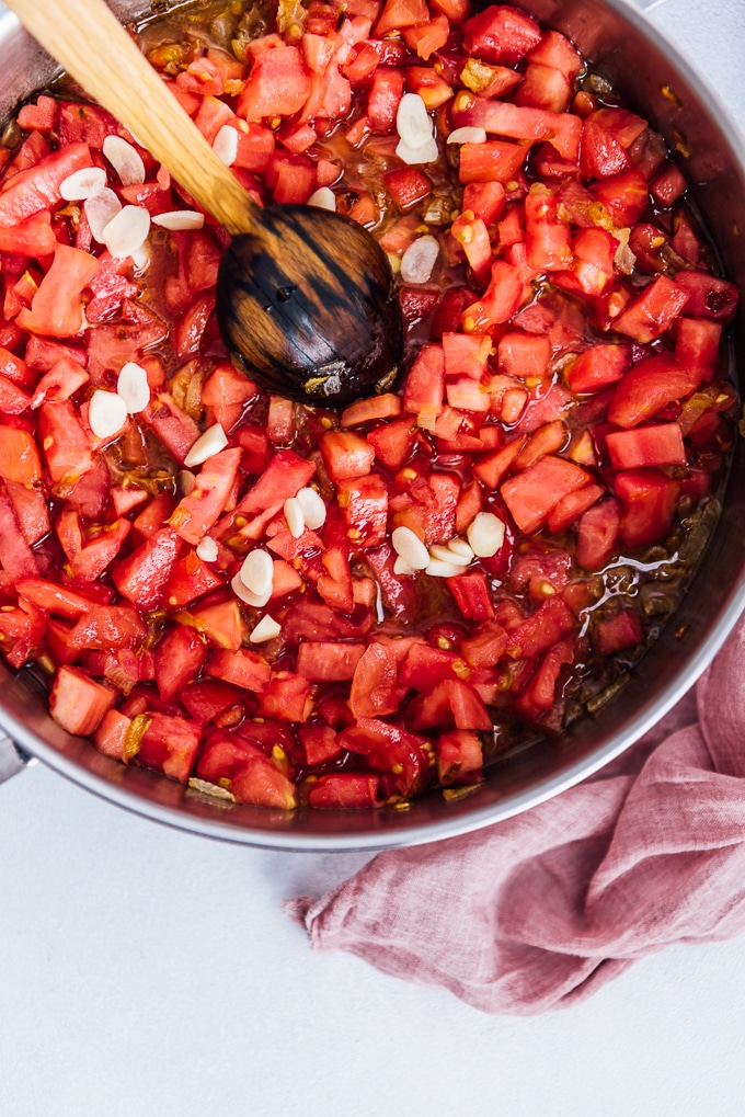 用平底锅和木勺煮西红柿和大蒜。