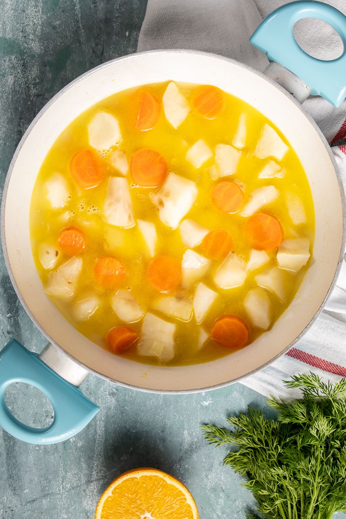 在白色的平底锅里放入切好的太阳蓟和胡萝卜，加入橙汁和柠檬汁。