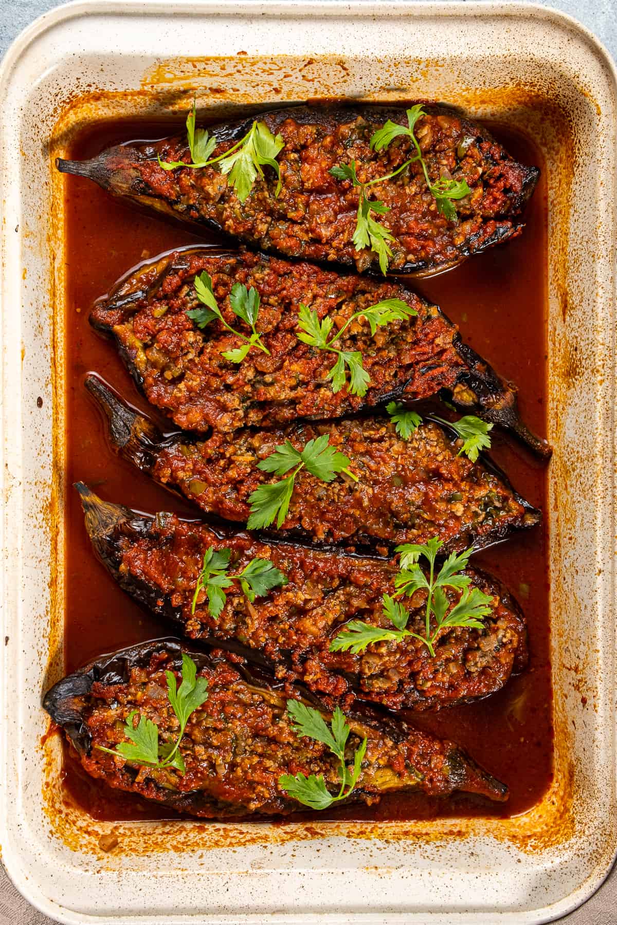 碎牛肉酿茄子在西红柿酱烘烤装饰用荷兰芹在烤盘。