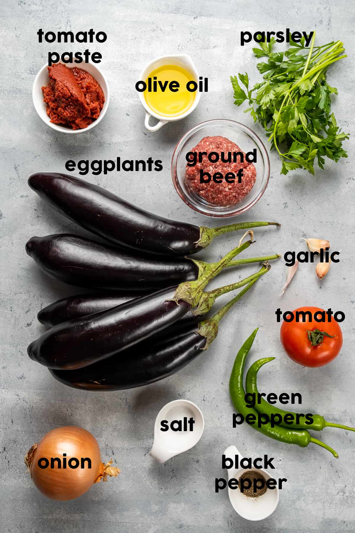 茄子，碎牛肉，番茄酱，橄榄油，土耳其青椒，番茄，蒜瓣，洋葱，欧芹在灰色背景上。