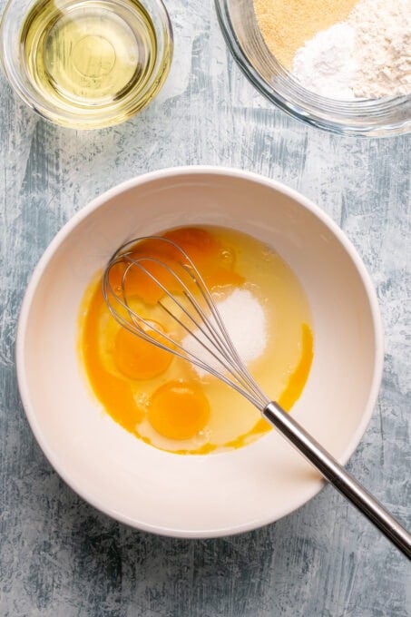 鸡蛋和糖放在一个大碗里，里面有一个打蛋器。