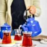 一名妇女用传统的茶杯从怀旧的茶壶里舀出土耳其茶。
