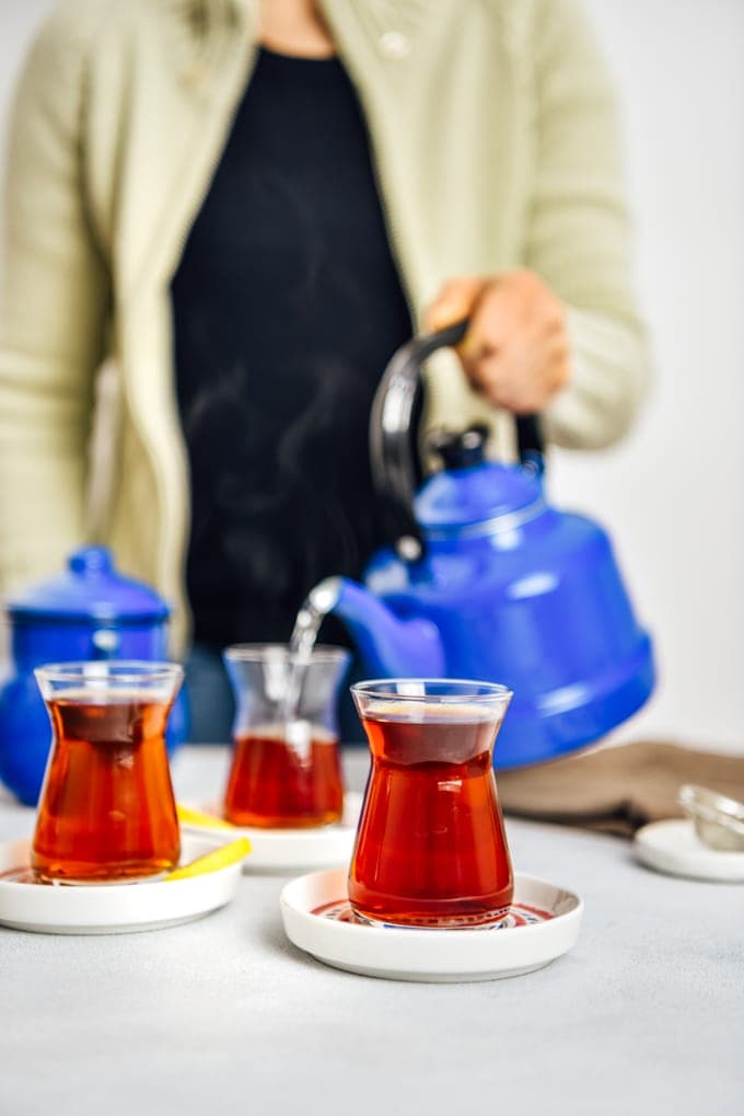 一名妇女用传统的茶杯从怀旧的茶壶里舀出土耳其茶。