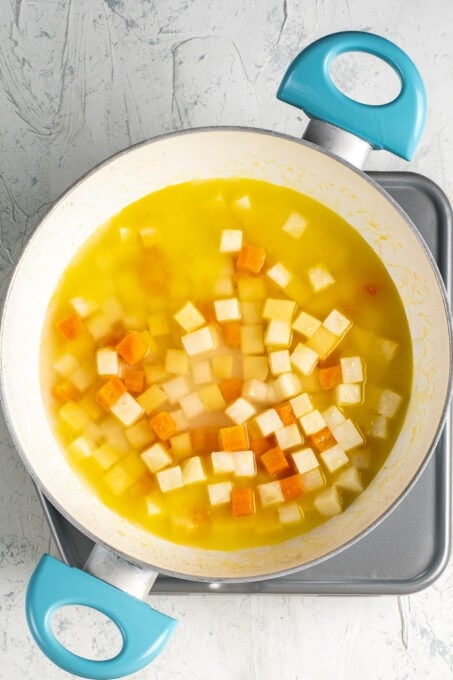 将块根芹、胡萝卜、榅桲和橙汁切成丁放在白锅里。