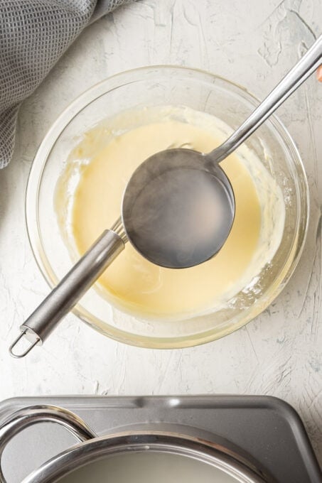 在玻璃碗中加入一勺热水，将酸奶混合物调温。