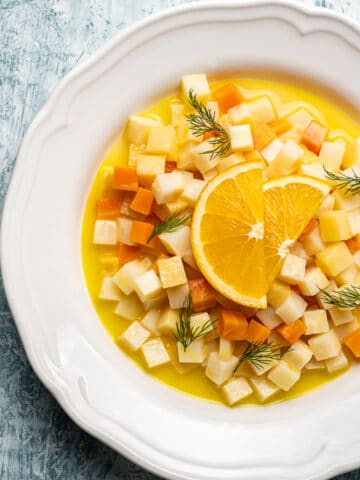 这是一款素食块根芹的食谱，用胡萝卜、木瓜和柑橘汁在白色的圆形盘子里浇上橘子角。