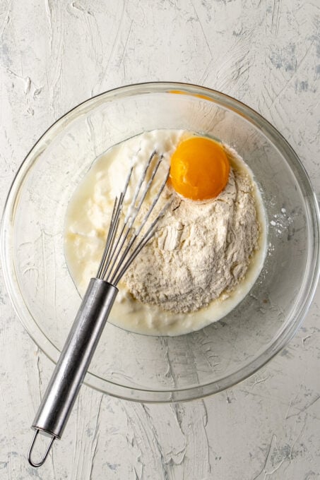 把酸奶、面粉和蛋黄放在一个玻璃碗里，用手搅拌。