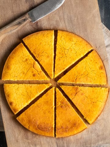 在圆锅里用热水烤玉米面包，在木板上切成片，旁边放一把刀。