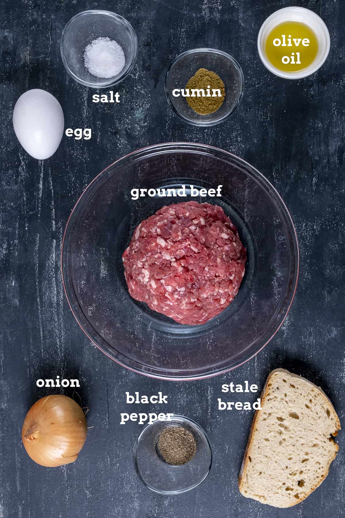 碎牛肉，鸡蛋，洋葱，一片面包，橄榄油，深色背景的香料。