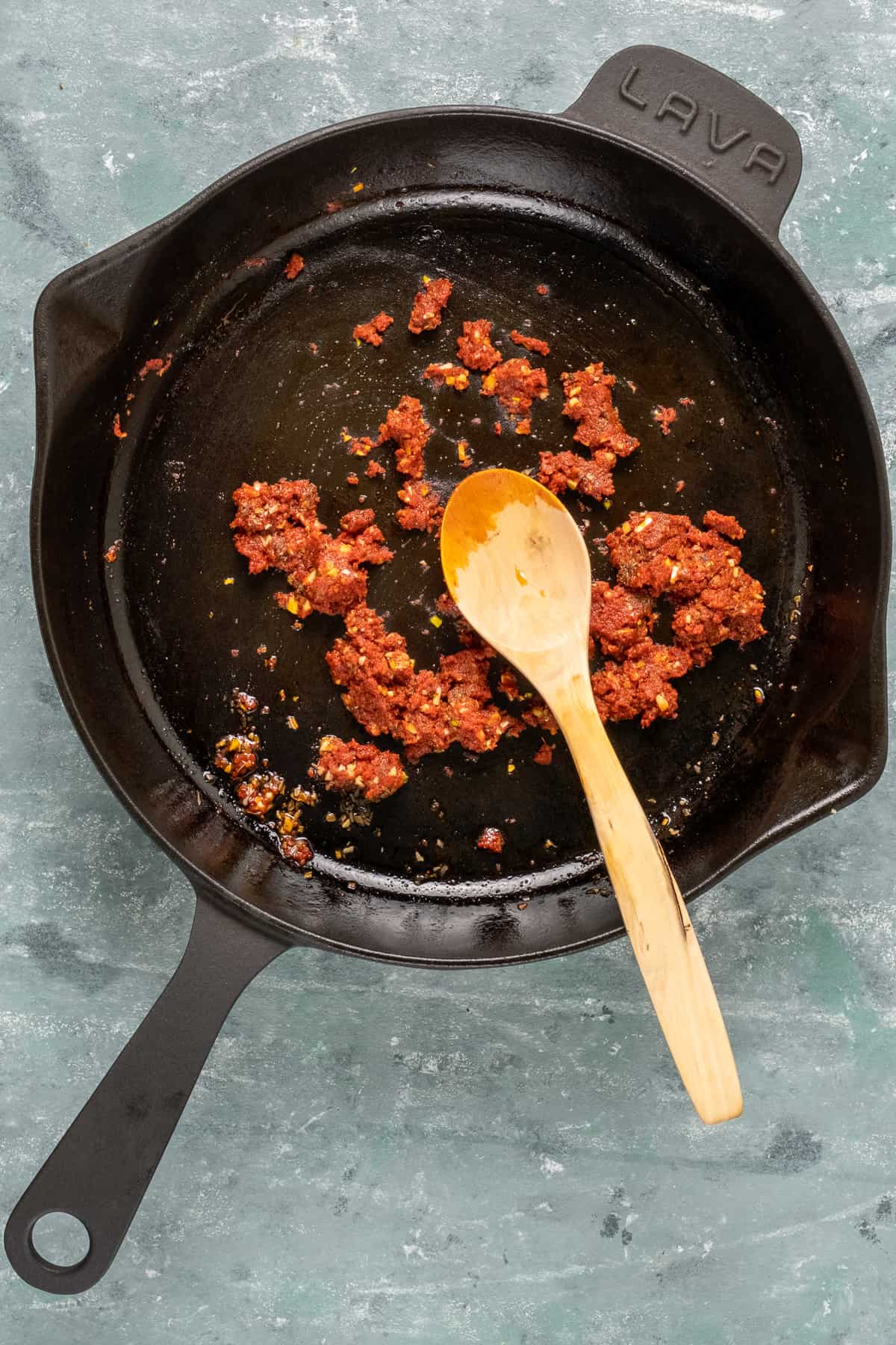 香料和蕃茄酱烹调在一个铸铁平底锅里面在它里面的匙子。