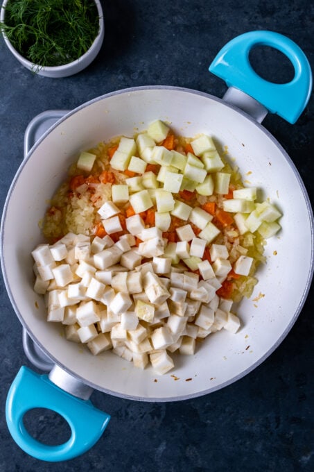 切成小切的洋葱，胡萝卜，苹果，芹菜根在白色盘子烹调。