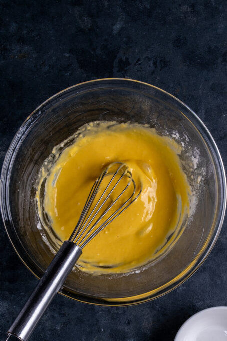 蛋黄，柠檬汁和面粉酱在玻璃碗和手中搅拌。