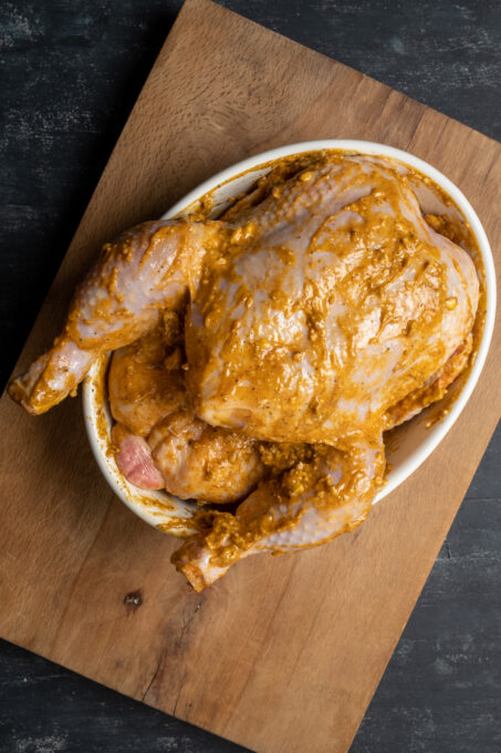 整只鸡涂上调味黄油，放在白色椭圆形平底锅中。