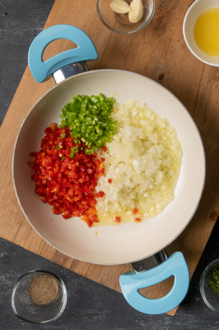将红椒、青椒和洋葱切碎，放入白锅中。