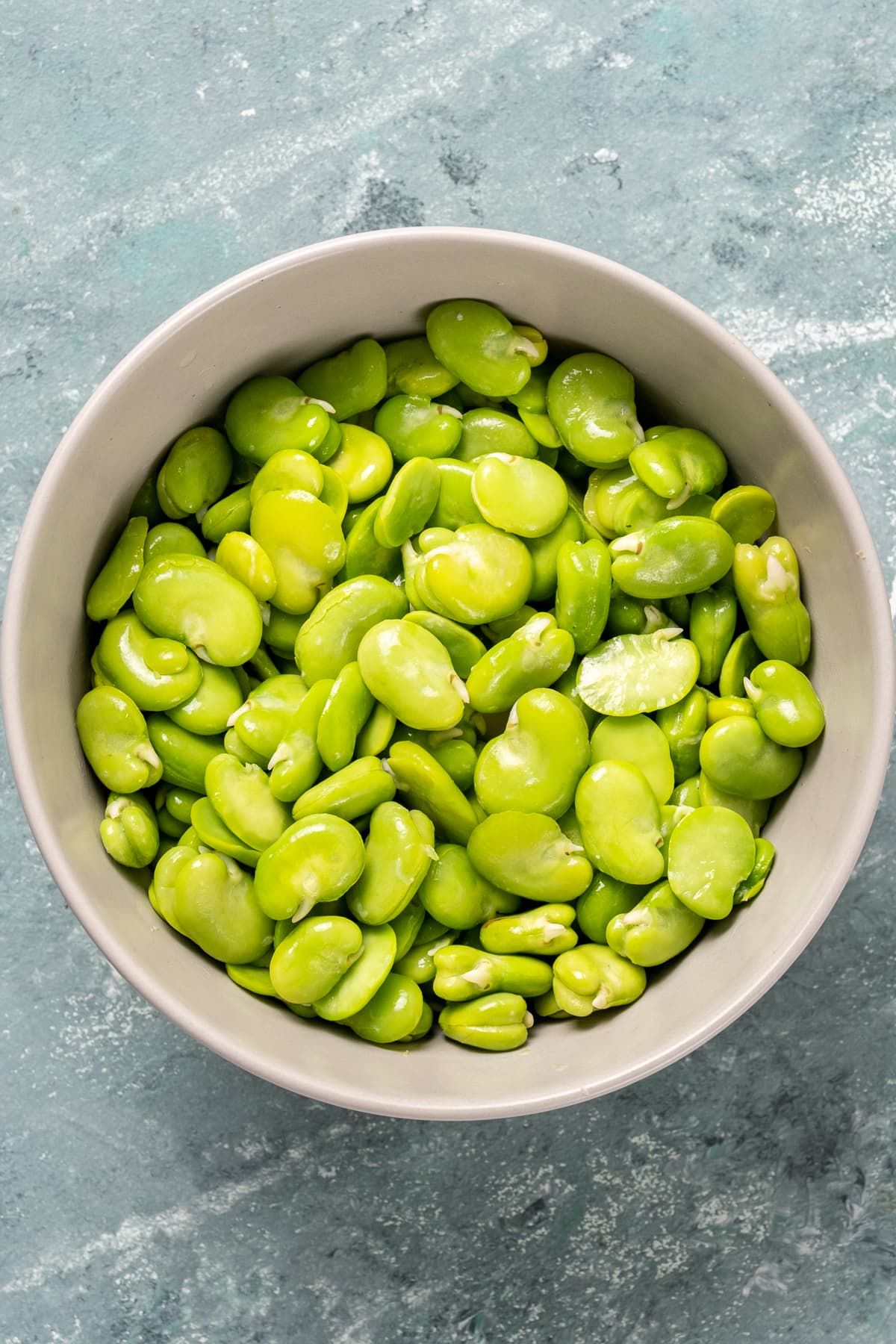 鲜绿色的蚕豆装在白色的碗里。