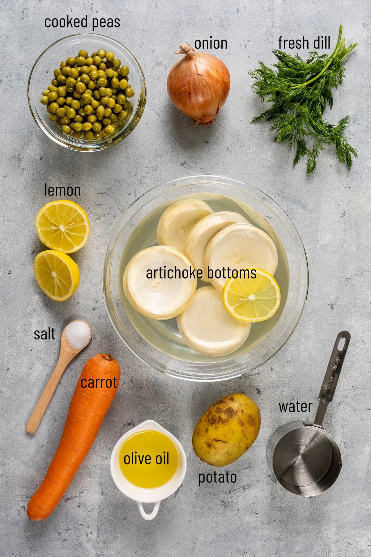 洋蓟底部、豌豆、洋葱、新鲜莳萝、柠檬、胡萝卜、土豆和橄榄油在灰色背景。