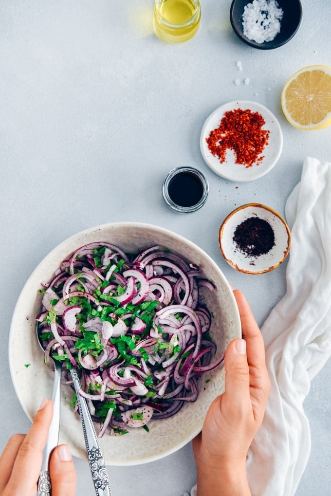 Would you like to take your picnic food to next level?Serve it with sumac onions! #sumac #turkishfood #onionsalad #onionrecipe 手在用白色的碗盛漆树洋葱