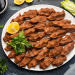 白色盘子里的土耳其雪茄配上上等碾碎肉和香料，旁边还有欧芹、柠檬角、石榴糖蜜和生菜叶。