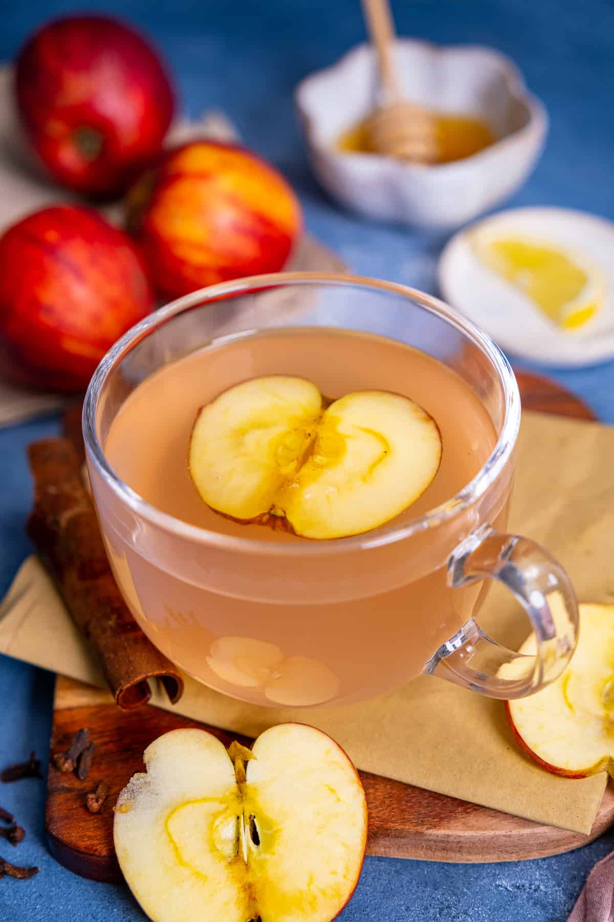 杯子里的苹果茶，后面是苹果、柠檬片和蜂蜜。