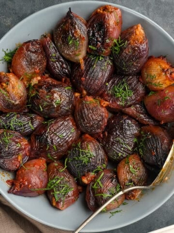 用番茄酱烤紫洋葱，配以切碎的欧芹，盛在盛有勺子的白碗里。