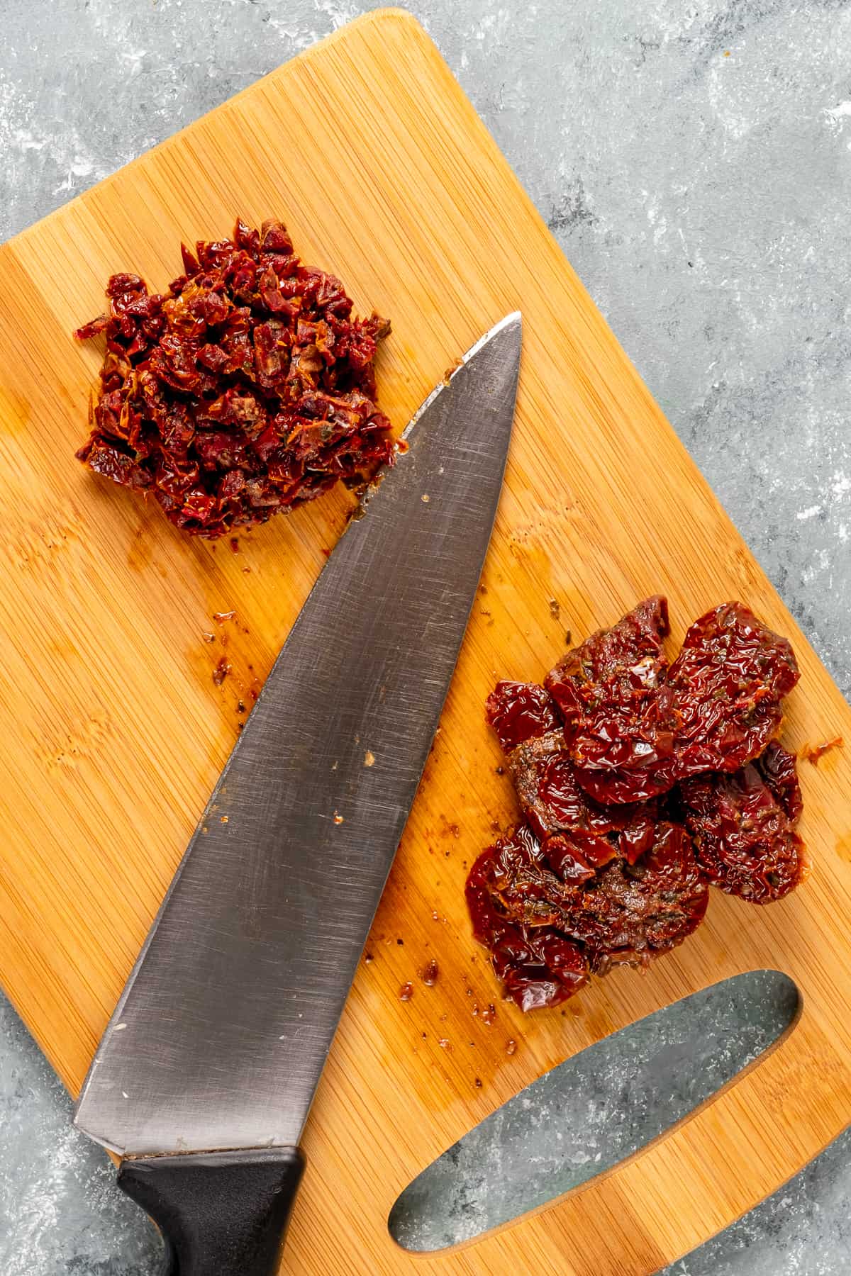 把晒干的西红柿整块切碎放在木板上，中间夹一把刀。