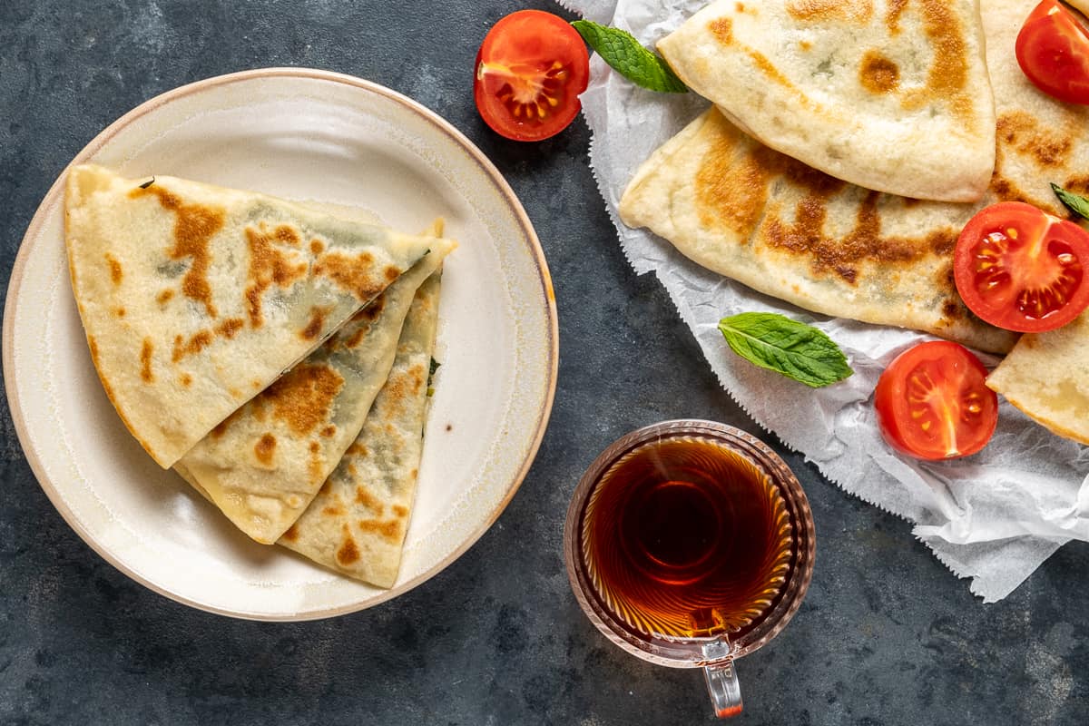 Gozleme切片放在盘子里，更多的放在更大的盘子里，配上一杯土耳其茶。