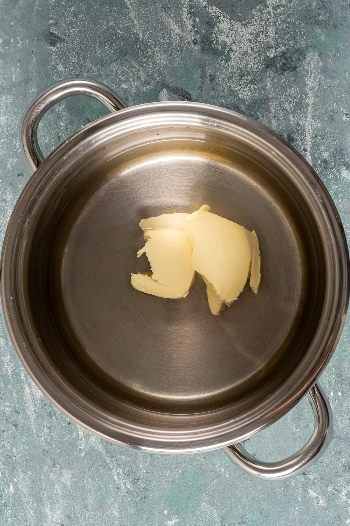 在平底锅里倒入黄油和水。