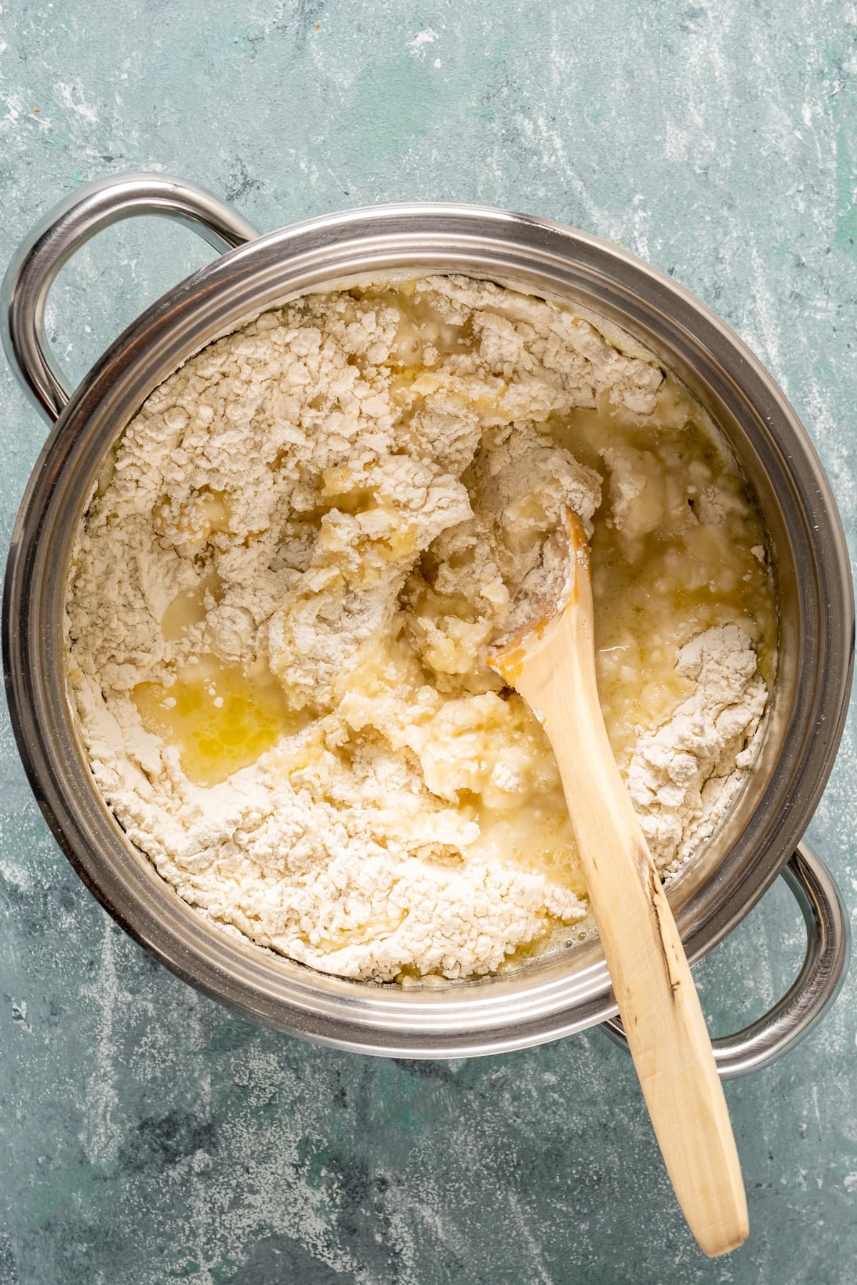 面粉，融化的黄油和水在平底锅里，里面放一个木勺。