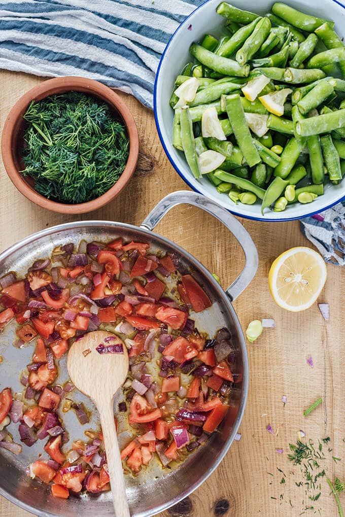 新鲜蚕豆与西红柿和洋葱一起用橄榄油炖煮，在室温下与柠檬和酸奶一起食用。这是我最喜欢的春天的无肉晚餐。