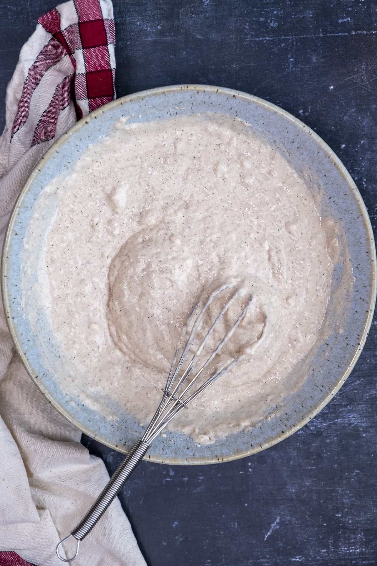 在一个蓝色的碗里放煎饼面糊，用手搅拌。