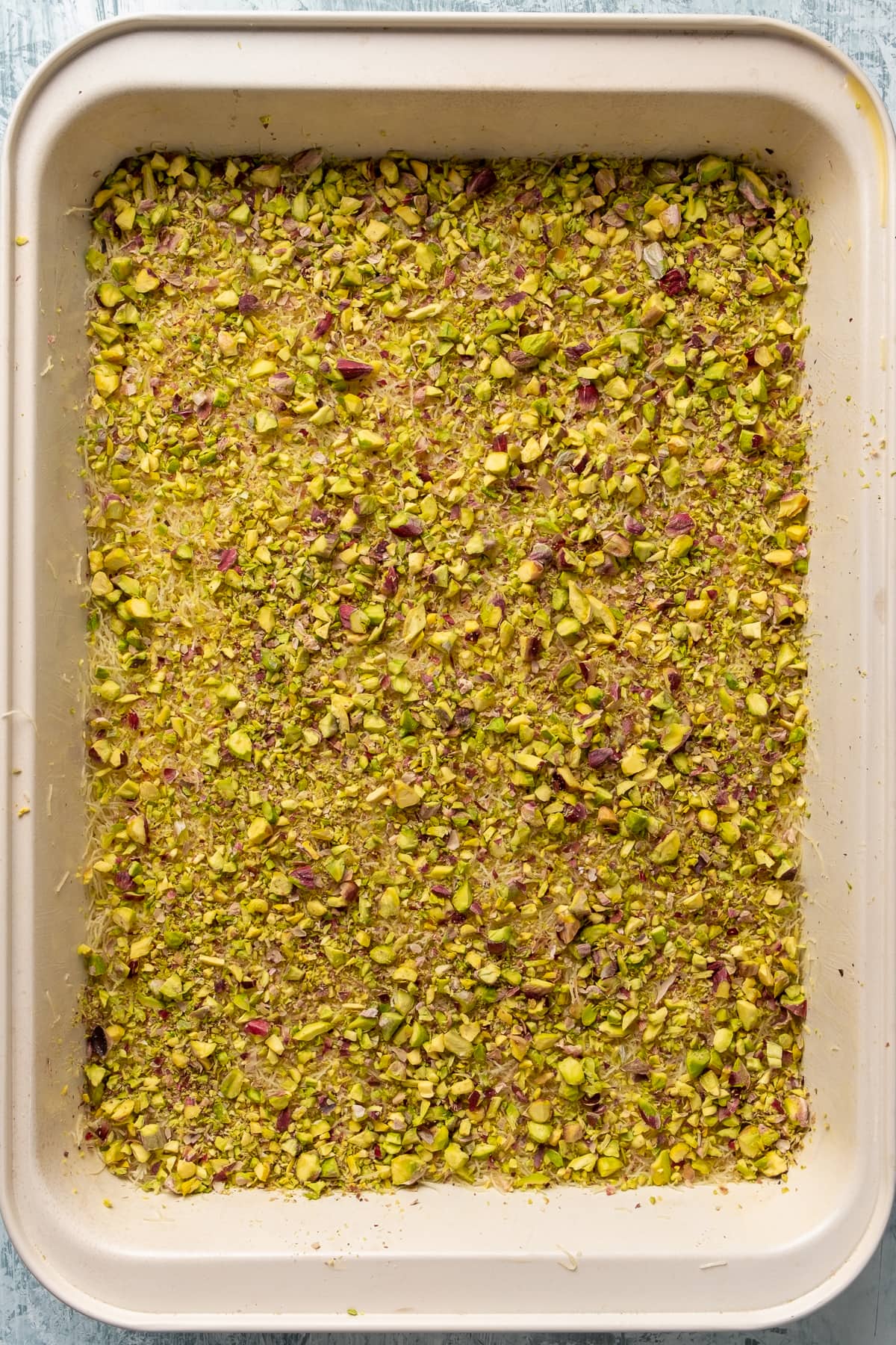 将切碎的卡达伊夫面团压平,上面撒上大量的开心果碎。