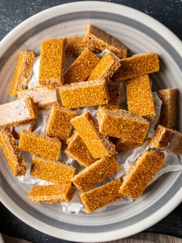 Sesame seed candies in small rectangular shape in a white bowl.