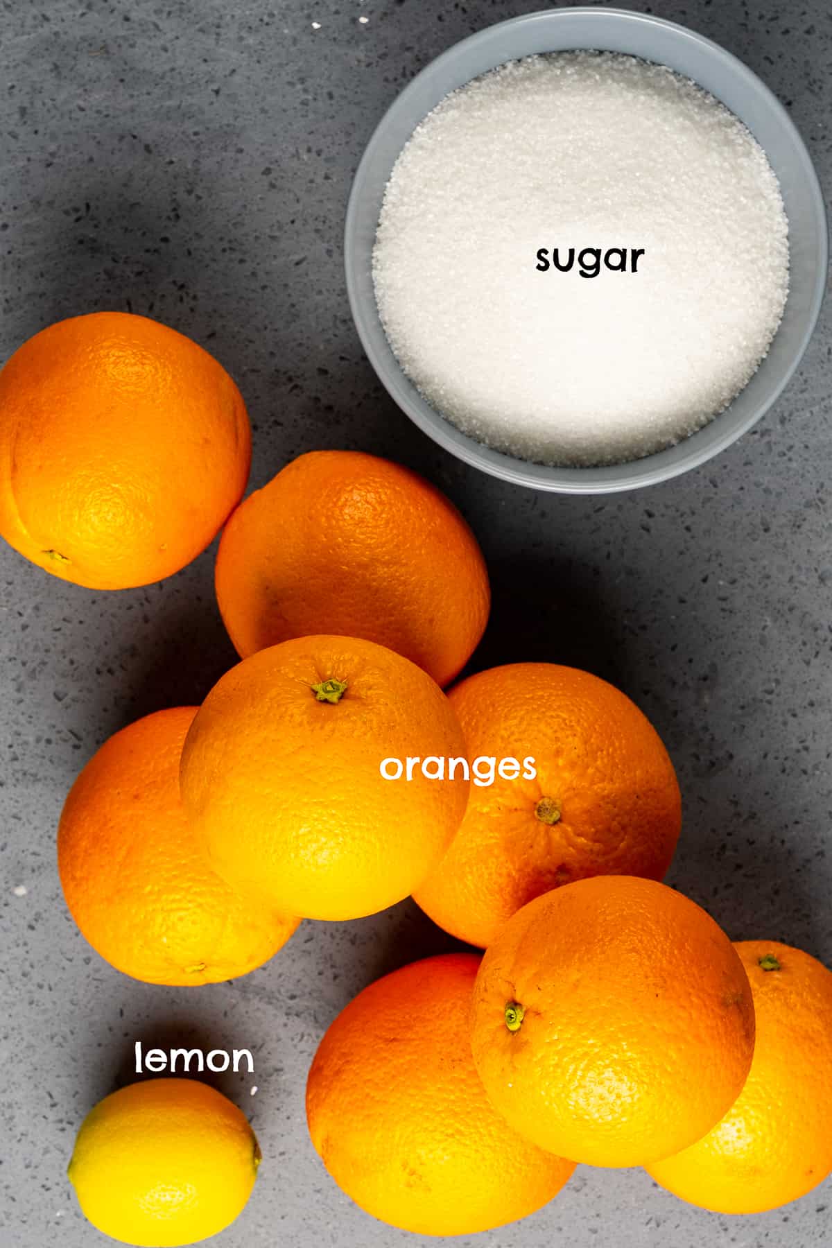 深色背景上有橘子、柠檬和一碗糖。