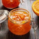 橘子酱装在玻璃罐里，旁边放一片橘子。
