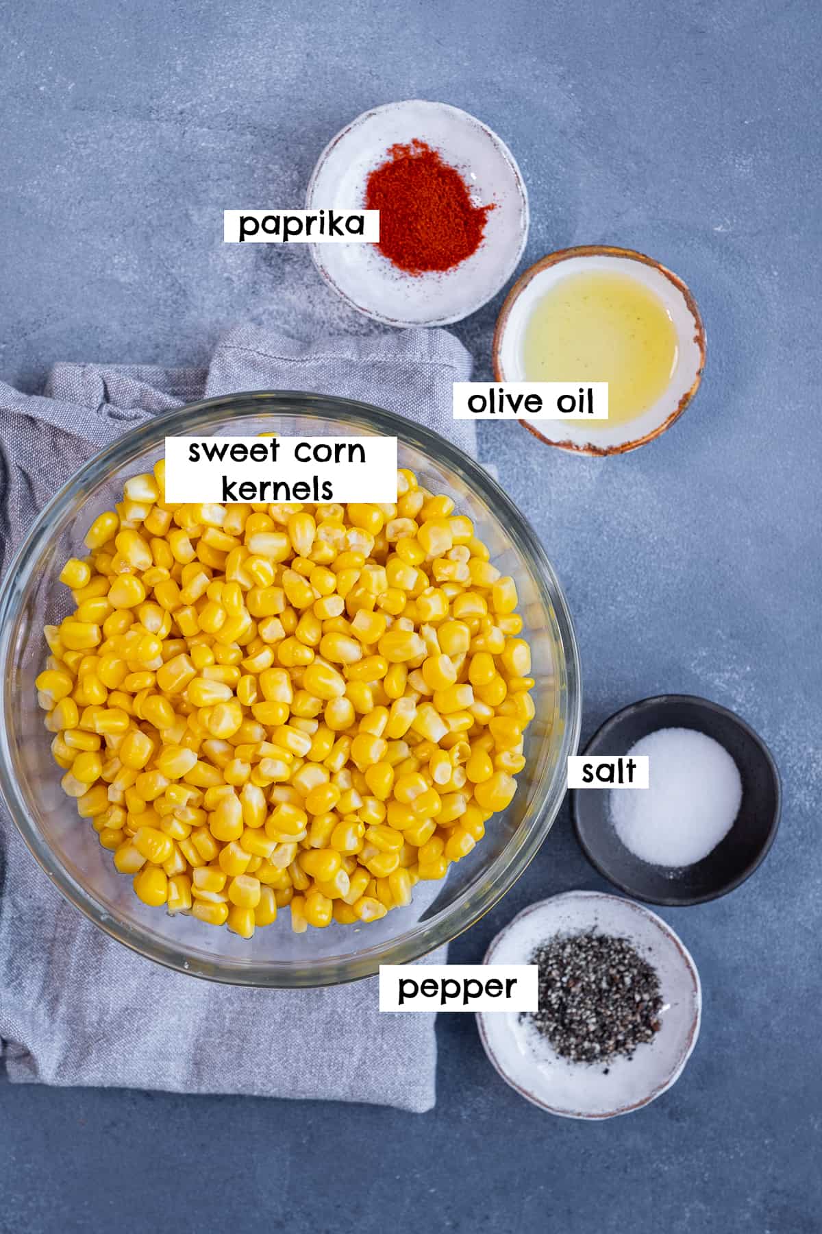 甜玉米粒、辣椒粉、油、盐和胡椒在灰色背景。