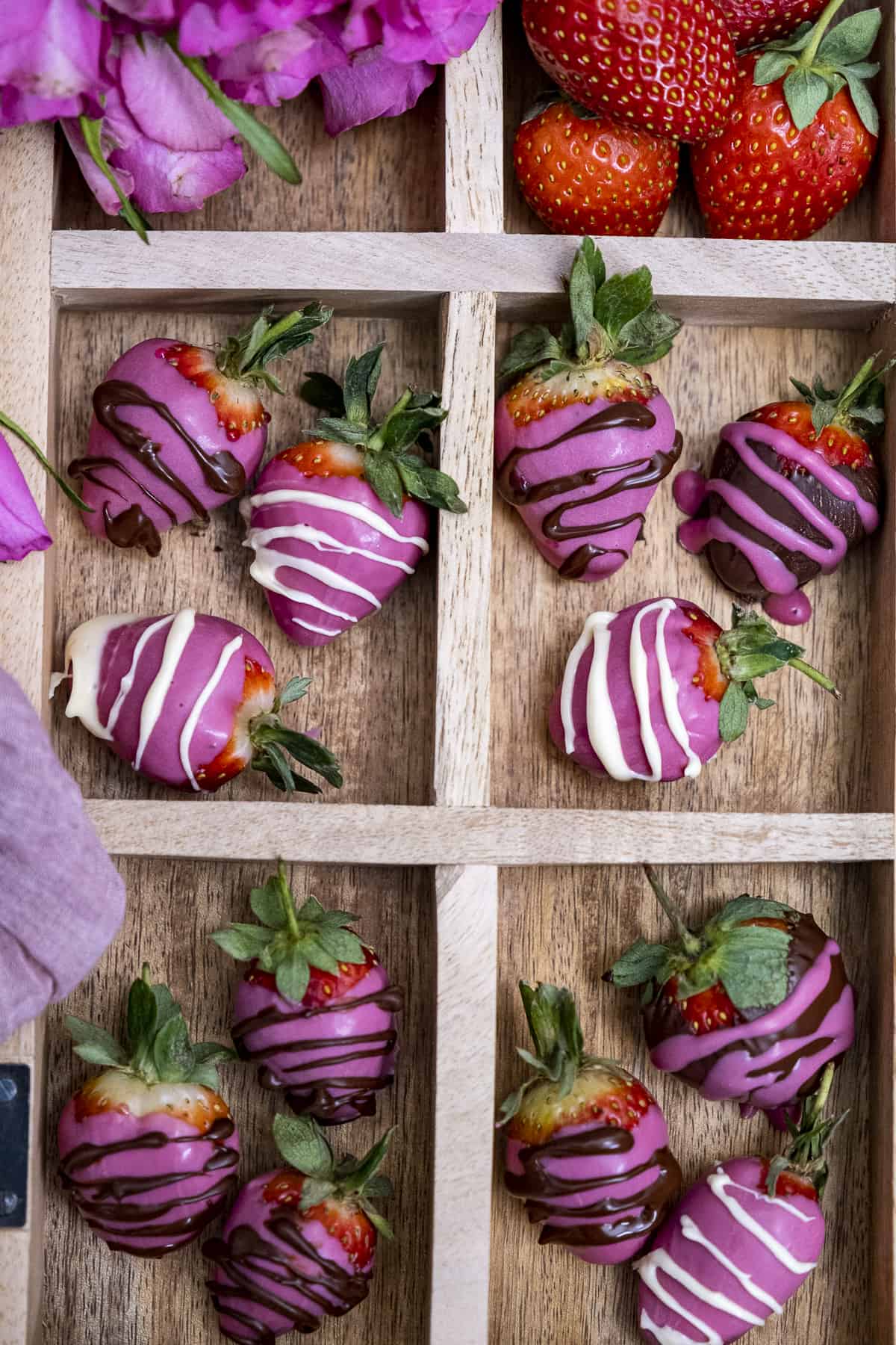 Pink chocolate covered strawberries, pink roses and plain strawberries in a wooden box with sections.