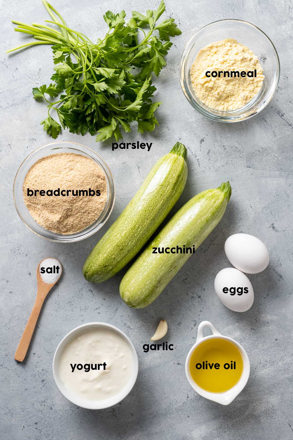 西葫芦，鸡蛋，玉米粉，欧芹，橄榄油，大蒜，盐和胡椒在灰色的背景上。