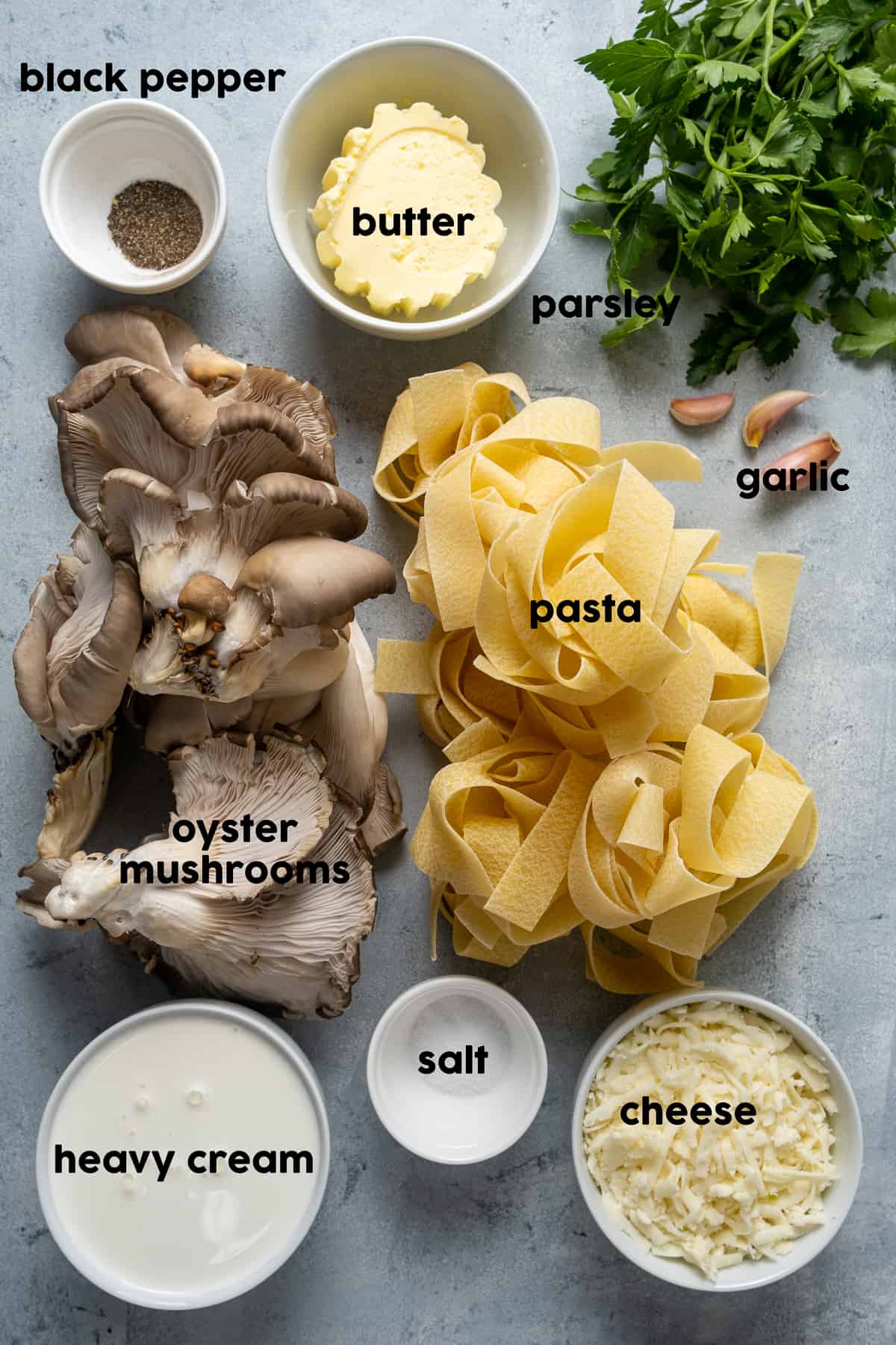 平菇，意大利面，蒜瓣，欧芹，黄油，浓奶油，磨碎的奶酪，盐和胡椒粉，灰色背景。
