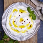 过滤酸奶淋上橄榄油，用新鲜薄荷叶和红辣椒片装饰，放在白色陶瓷盘上。