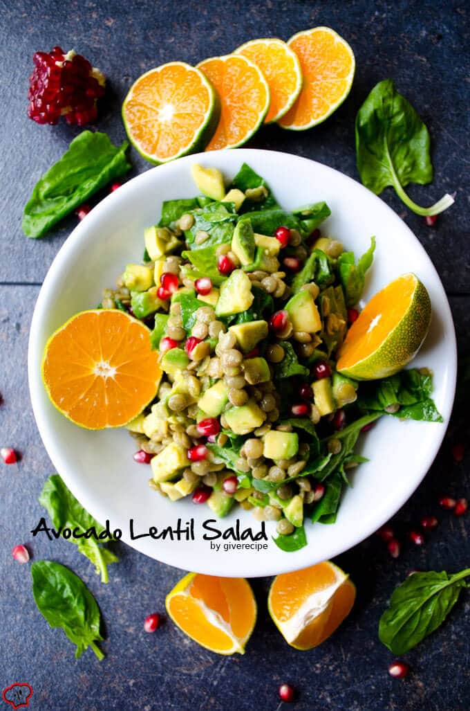 This Green Lentil Salad is packed with vitamins, so perfect for chilly fall days. This vegan and gluten free salad is a real immune system booster! #vegetarian #lentilsalad #greenlentil #vegansalad #healthysalad 绿扁豆沙拉,牛油果,桔子,菠菜和石榴在一个白色的碗。