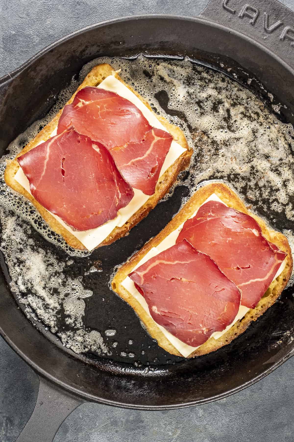 面包片上面撒上奶酪和冷肉片在平底锅里煎。