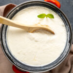 用搪瓷锅自制酸奶，里面放一个木勺，顶部放一小枝新鲜薄荷。