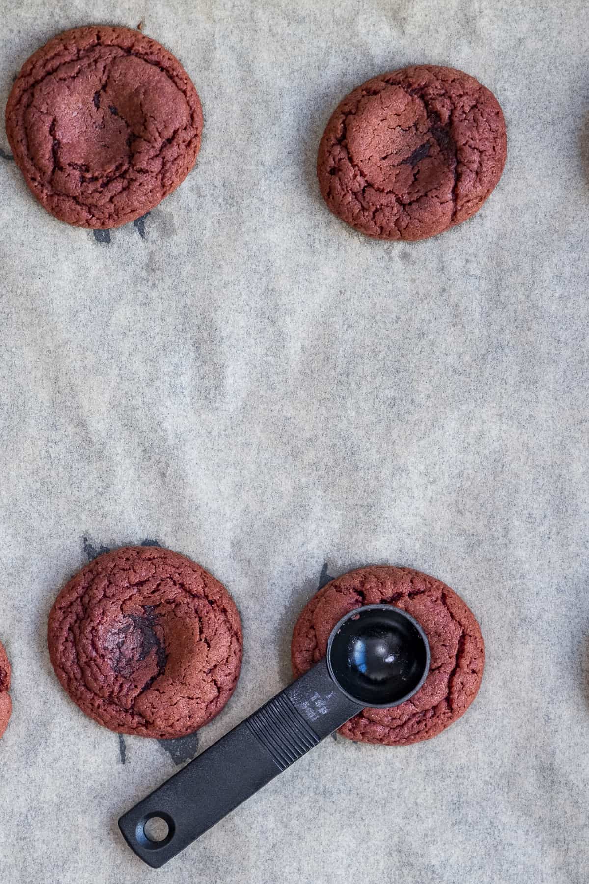 用黑色茶匙在烤盘上烤好的红丝绒饼干上压痕。