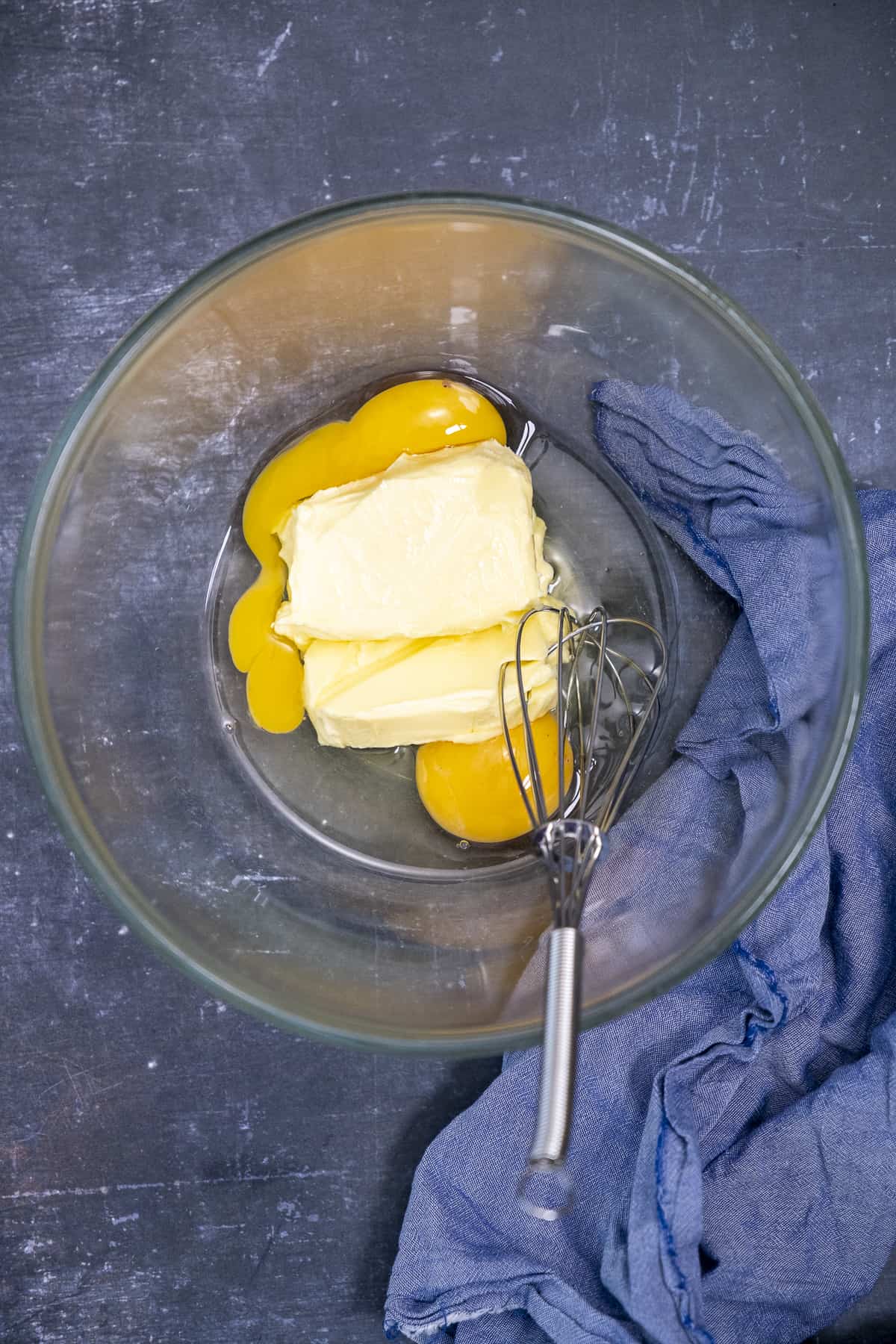 把黄油和鸡蛋放在玻璃碗里，用手搅拌。