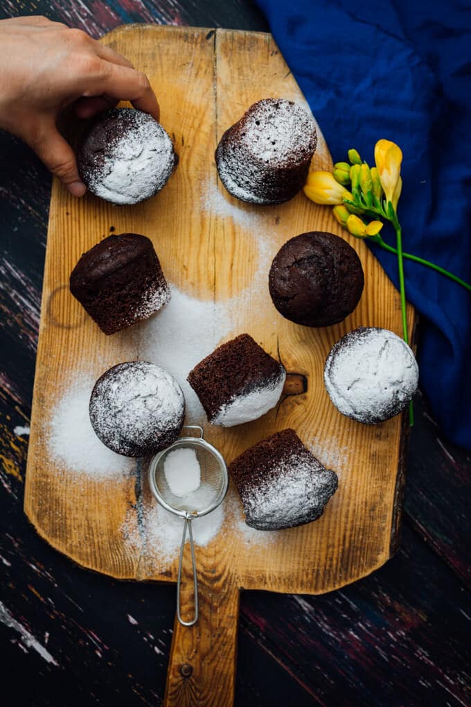 These Buttermilk Chocolate Muffins are perfectly moist, tender and chocolatey. You will feel like you’re eating brownies in each bite. These make a wonderful grab and go breakfast or a quick after school snack. #chocolatemuffins #muffinrecipe #buttermilkmuffins 抓住一个白脱牛奶巧克力松饼了糖粉在木板上