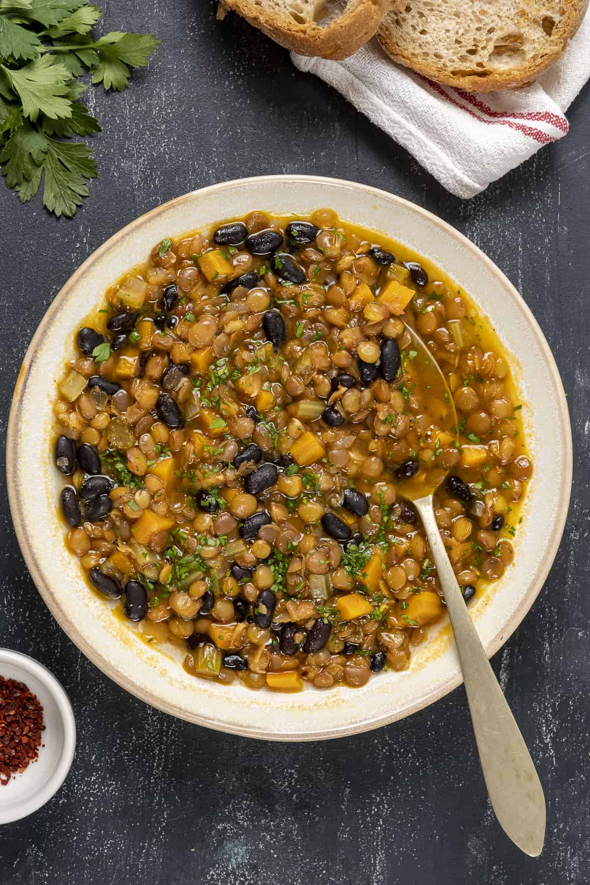 Black bean lentil soup in a white bowl and a spoon in it.